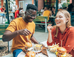 two young adults eating hamburgers and fries