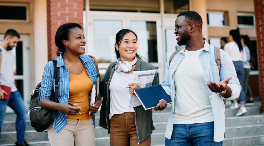 three young adults standing outside of an academic building
